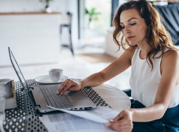 business woman reviewing documents by her home laptop