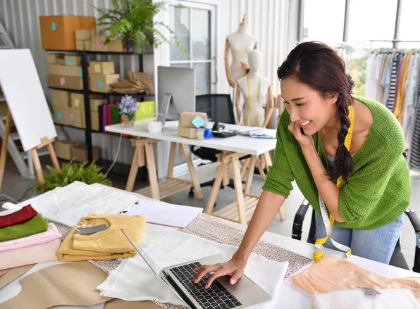 female business owner on the phone smiling while typing on her laptop